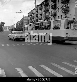 Photo d'archive de la circulation urbaine à Sloviansk, 1976, avec un trolleybus ZiU-9 et une voiture 'Moskvich-412' sur fond de bâtiments de cinq étages, comme symbole de la vie quotidienne urbaine paisible soviétique Banque D'Images