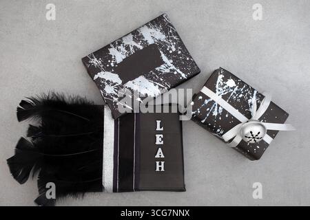 cadeaux enveloppés de noir et décorés de différentes manières. certains ont des éclaboussures de peinture argentée, d'autres ont des rubans, des plumes et des cloches Banque D'Images