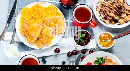 Crêpes fraîches avec confiture, fruits et baies sur fond gris. Délicieuses crêpes maison. Vue de dessus Banque D'Images