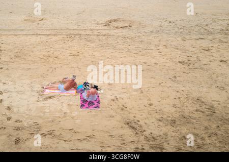Un couple de vacanciers matures se relaxant sur Towan Beach à Newquay en Cornouailles au Royaume-Uni. Banque D'Images