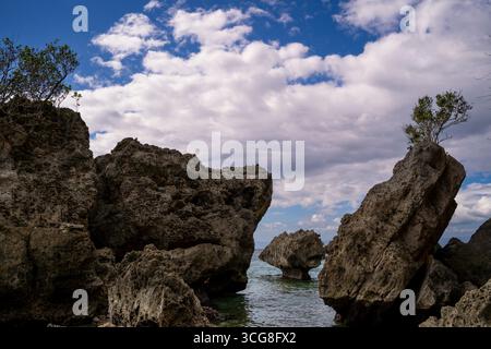 Vue de formations calcaires escarpées résistantes contre la mer turquoise sous un vaste ciel strié de nuages, Guimaras, Visayas occidentales, Philippines. Banque D'Images
