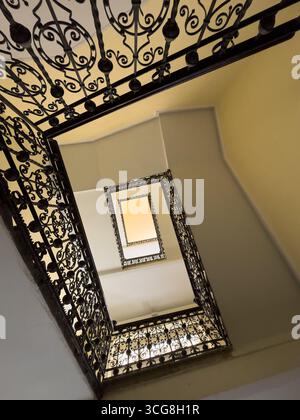 Vue sur un escalier en colimaçon avec balustrade complexe en fer forgé. Capture la beauté architecturale et la symétrie des conceptions classiques, évoquant l'élégance et l'art intemporel. Banque D'Images