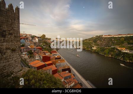 Vue aérienne du fleuve Douro serpentant à travers Porto, avec des toits en terre cuite contrastant avec les anciens murs de pierre et les collines verdoyantes, Porto, Portugal. Banque D'Images