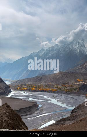 Vue d'une rivière tressée serpentant à travers un paysage accidenté avec des montagnes enneigées perçant le ciel, une danse de la terre et du ciel, Hunza Nagar, Gilgit Banque D'Images