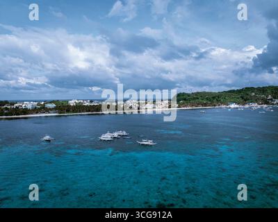 Vue aérienne des eaux Azur rencontrant les plages de sable blanc et les bâtiments de Boracay, contrastant avec un ciel dramatique, Boracay, Aklan, Philippines. Banque D'Images