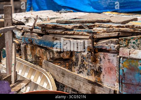 Dakar, Sénégal - 12 mai 2025 : vue de structures en bois altérées à la plage de Soumbédioune, où les textures de bois vieilli rencontrent la peinture bleue décolorée sous une bâche drapée. Banque D'Images