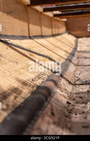 Dakar, Sénégal - 12 mai 2025 : vue sur la plage de Soumbédioune, où le bois brut texturé d'un bateau traditionnel se courbe, révélant la couture sombre contre les planches altérées. Banque D'Images