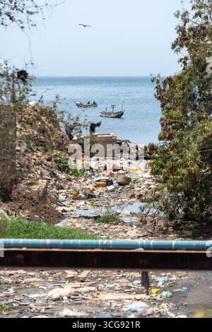 Dakar, Sénégal - 12 mai 2025 : vue sur la plage de Soumbédioune où les bateaux de pêche vibrants contrastent avec la dure réalité de l'accumulation de déchets, une réflexion poignante sur les défis environnementaux. Banque D'Images