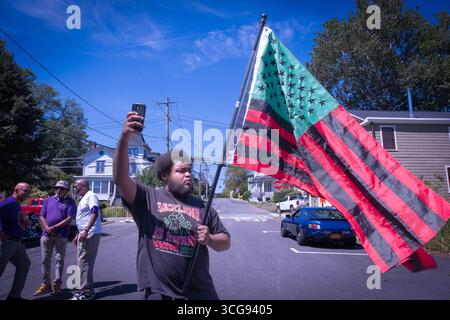 A l'African American Day Parade.a jeune homme prend un selfie avec le drapeau vert noir rouge afro américain. À Nyack, comté de Rockland, New York. Banque D'Images