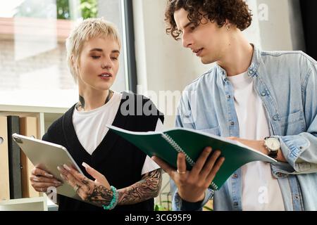 Deux jeunes personnes participent à des discussions productives tout en examinant des documents dans un bureau. Banque D'Images