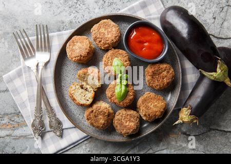 Délicieux beignets d'aubergines frits servis avec de la sauce tomate en gros plan dans une assiette sur la table. Vue horizontale de dessus Banque D'Images