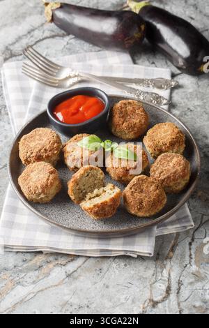 entrée d'aubergines frites boules d'aubergines végétariennes avec sauce tomate et épices gros plan dans l'assiette sur la table. Vertical Banque D'Images