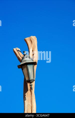 Une lampe rustique sur un poteau en bois contre un ciel bleu clair, Banque D'Images