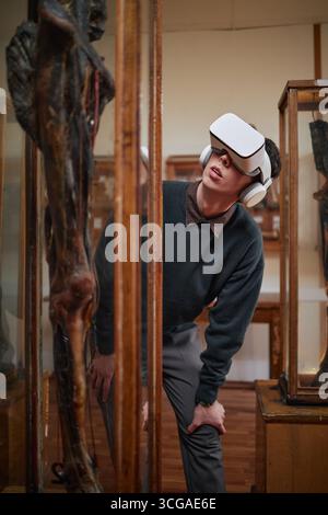 Jeune homme caucasien adulte portant un casque de réalité virtuelle Exploring Museum exposition Banque D'Images