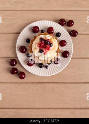 Gros plan d'une tarte avec de la crème fouettée et des baies fraîches mélangées sur une assiette blanche Banque D'Images