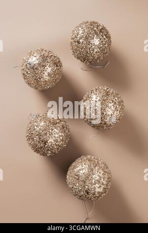 Boules brillantes dorées de Noël sur fond beige. Carte de voeux créative de Noël. Concept du nouvel an. Mousse moka. Vue de dessus. Banque D'Images