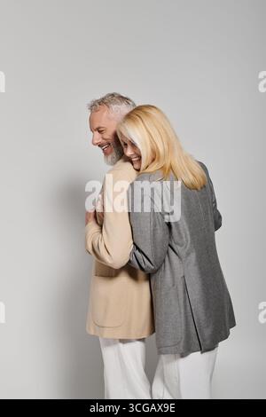 Couple senior aimant profite d'un moment tendre tout en vêtu de tenues chics, rayonnant de bonheur. Banque D'Images