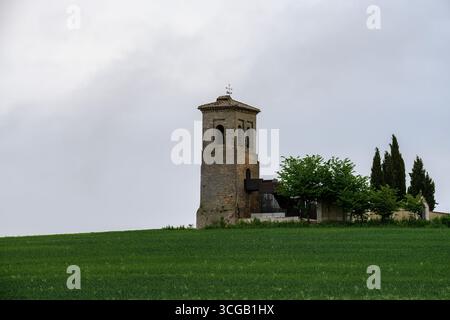 Clocher historique en briques à côté d'un cimetière rural, entouré d'arbres et de champs verdoyants Banque D'Images