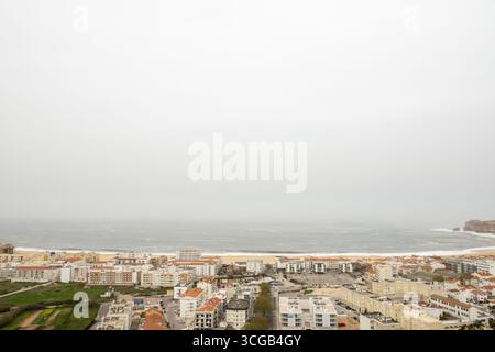 Ville côtière de Nazare au Portugal avec une plage magnifique et une vue panoramique sur l'océan d'en haut par une journée grise et nuageuse Banque D'Images