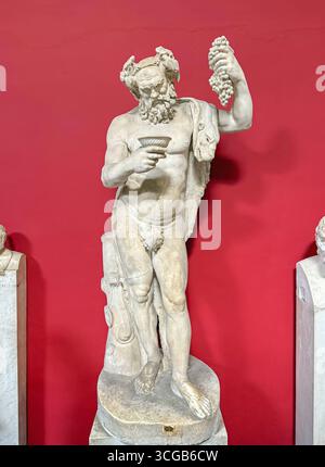 CITÉ DU VATICAN, ROME, ITALIE - 02 AOÛT 2025 statue en marbre de Silène tenant un bouquet de raisins et une tasse de vin, exposée sur un piédestal Banque D'Images