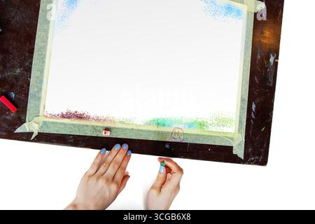 Main commençant le dessin pastel sur papier avec cadre de ruban de masquage. Vue de dessus des mains commençant un dessin pastel sur une feuille de papier blanche, Banque D'Images