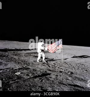 Conrad se déploie un drapeau. L'astronaute de la mission Apollo 12 Charles "Pete" Conrad se trouve à côté du drapeau des États-Unis après l'Est a été déployé sur la surface lunaire au cours de la première activité extravéhiculaire (EVA-1), le 19 novembre 1969. Plusieurs empreintes prises par l'équipage peut être vu dans la photographie. Photographe : Alan Bean de la NASA Banque D'Images