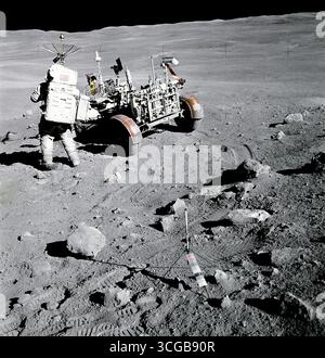 L'astronaute Apollo 16 Charles M. Duc Jr., pilote du module lunaire "Orion", se dresse près de la Rover, Rover lunaire (LRV) à la Station no. 4, près de Stone Mountain, au cours de la deuxième Apollo 16 activité extravéhiculaire (EVA-2) à l'atterrissage de Descartes. Les rayons de lumière de l'Ray cratère peut être vu en haut à gauche. Le gnomon, qui est utilisé comme une référence photographique pour établir l'angle du soleil vertical locale, l'échelle, et couleur lunaire, est déployée dans le centre avant-plan. Remarque l'angularité des roches dans la région. Photographe : NASA/ John Young Banque D'Images