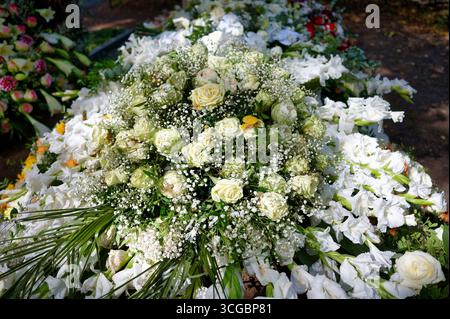 Décoration de tombe élégante festive faite de roses de couleur crème nichée dans Gypsophila et bordée de glaïeuls blancs Banque D'Images