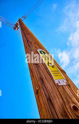 Poteau utilitaire en bois avec identification de l'énergie et lignes électriques contre Blue Sky Banque D'Images