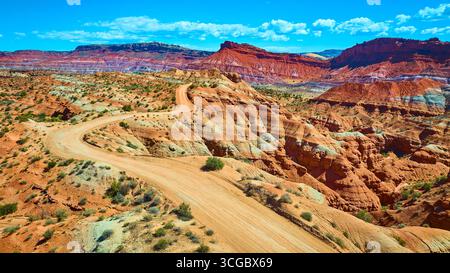Route de terre sinueuse aérienne à travers les Badlands et Mesas colorés de l'Utah Banque D'Images