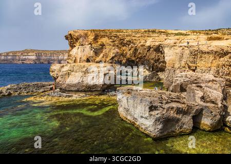 Gozo, Malte – 23 juin 2021 : les touristes explorent les falaises de calcaire escarpées surplombant la mer Méditerranée. Banque D'Images