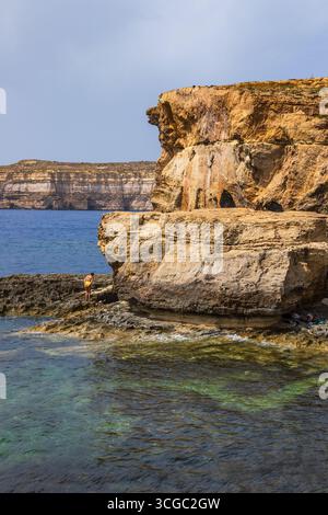 Gozo, Malte – 23 juin 2021 : les touristes explorent les falaises de calcaire escarpées surplombant la mer Méditerranée. Banque D'Images