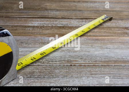Une vue d'un outil de ruban à mesurer jaune commun sur une surface en bois montrant une distance de 12 pouces. Banque D'Images