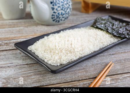 Une vue d'un plat noir avec du riz à sushi ou du riz à grains courts, dans un cadre de nature morte. Banque D'Images