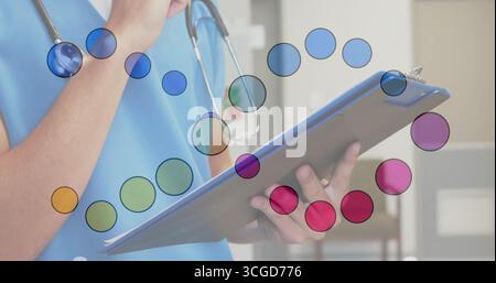 Infirmière en gommage bleu examinant les notes sur le presse-papiers bleu dans la salle de clinique, portant un stéthoscope Banque D'Images