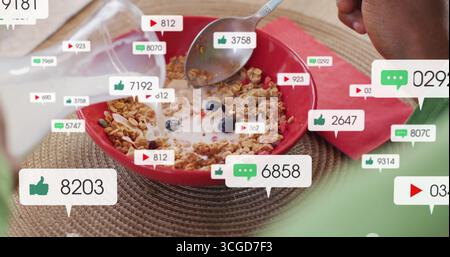 Verser le lait à la main dans un bol rouge et remuer le granola avec des myrtilles au coin petit déjeuner, icônes sociales Banque D'Images