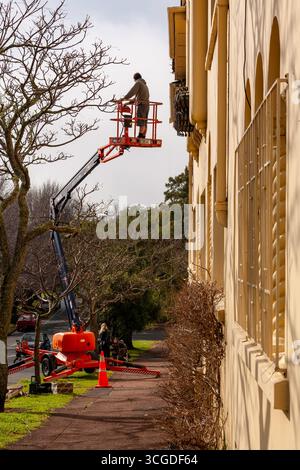 homme dans l'air deux étages cherry picker foot path travail tradie australien commerçant travailleur qualifié mph 13/15 Banque D'Images