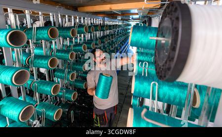PRODUCTION - 26 août 2025, Saxe, Chemnitz : Rico Neumann travaille sur une machine à tisser pour tapis de glissement textile dans l'usine de production de Mr. Snow à Chemnitz. Environ 13 000 fils se réunissent ici et sont tissés en boucles flexibles. La structure offre une bonne surface de contact pour les carres des skis. La société basée à Chemnitz dessert désormais tout le spectre du ski, du ski de fond classique aux pistes freestyle. Dimanche (31.08.2025), la dernière installation avec de la neige textile de Chemnitz ouvrira au Danemark, une arène de ski de 5 000 mètres carrés à 360 degrés avec six pistes différentes, i Banque D'Images