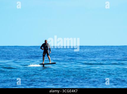 Un homme sur une planche de surf e foil au large de la plage de Beadnell dans le Northumberland, au Royaume-Uni. Banque D'Images