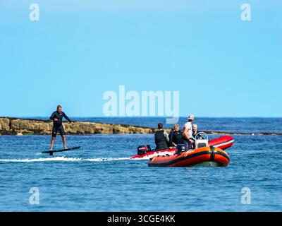 Un homme sur une planche de surf e foil au large de la plage de Beadnell dans le Northumberland, au Royaume-Uni. Banque D'Images