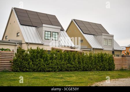 Tygelsjö, Suède ; 4 août 2025 : deux maisons suédoises modernes avec toits en zinc métallique et panneaux solaires et haie de jardin. Banque D'Images