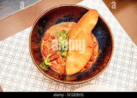 Cuisine traditionnelle géorgienne de légumes lobio apéritif rouge haricots rouges dans une assiette noire sur la table du restaurant Banque D'Images