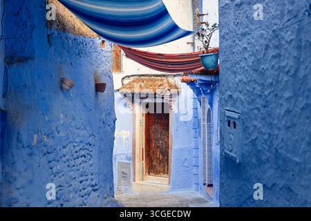 Ruelle étroite dans la médina de Chefchaouen, Maroc – « la ville bleue » – avec des murs et des portes peints au cobalt, des lampadaires suspendus. Banque D'Images