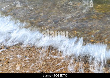 Vagues floues sur le bord de mer de la plage de galets et de galets à Whitstable sur la côte nord du Kent. Une longue exposition produit l'effet flou. Banque D'Images