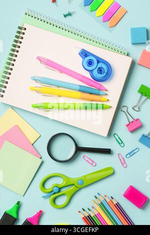Fournitures scolaires ou papeterie de bureau sur fond bleu. Vue de dessus avec espace pour le texte. Banque D'Images