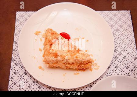 Morceau de gâteau sucré pâtissier Napoléon sur assiette blanche sur table dans le restaurant Banque D'Images