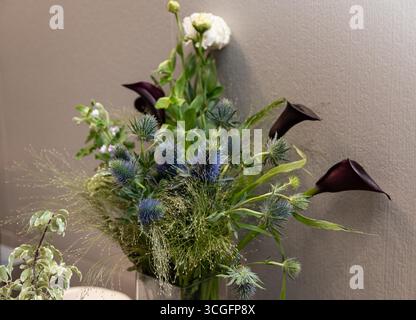 Un arrangement floral sophistiqué avec chardons éclatants, lys sombres élégants et œillets blancs délicats dans un vase. parfait pour ajouter elegan Banque D'Images