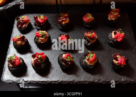 Une sélection de canapés gastronomiques élégamment disposés sur un plateau en ardoise. chaque friandise en bouchée est surmontée de garnitures vibrantes, un présentat sophistiqué Banque D'Images