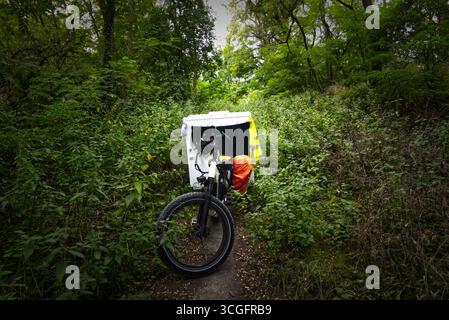 Fatbike avec une petite remorque de camping-car garée sur un sentier vert dans les bois, prêt pour une micro-aventure Banque D'Images