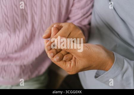 Couple heureux passant du temps de qualité ensemble dans une maison moderne confortable. Ils ont une conversation, buvant du café pendant que la femme est assise sur un canapé et Banque D'Images